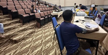 Pemeriksaan tekanan darah seorang pekerja semasa program kesihatan pekerjaan bersama KOSMA