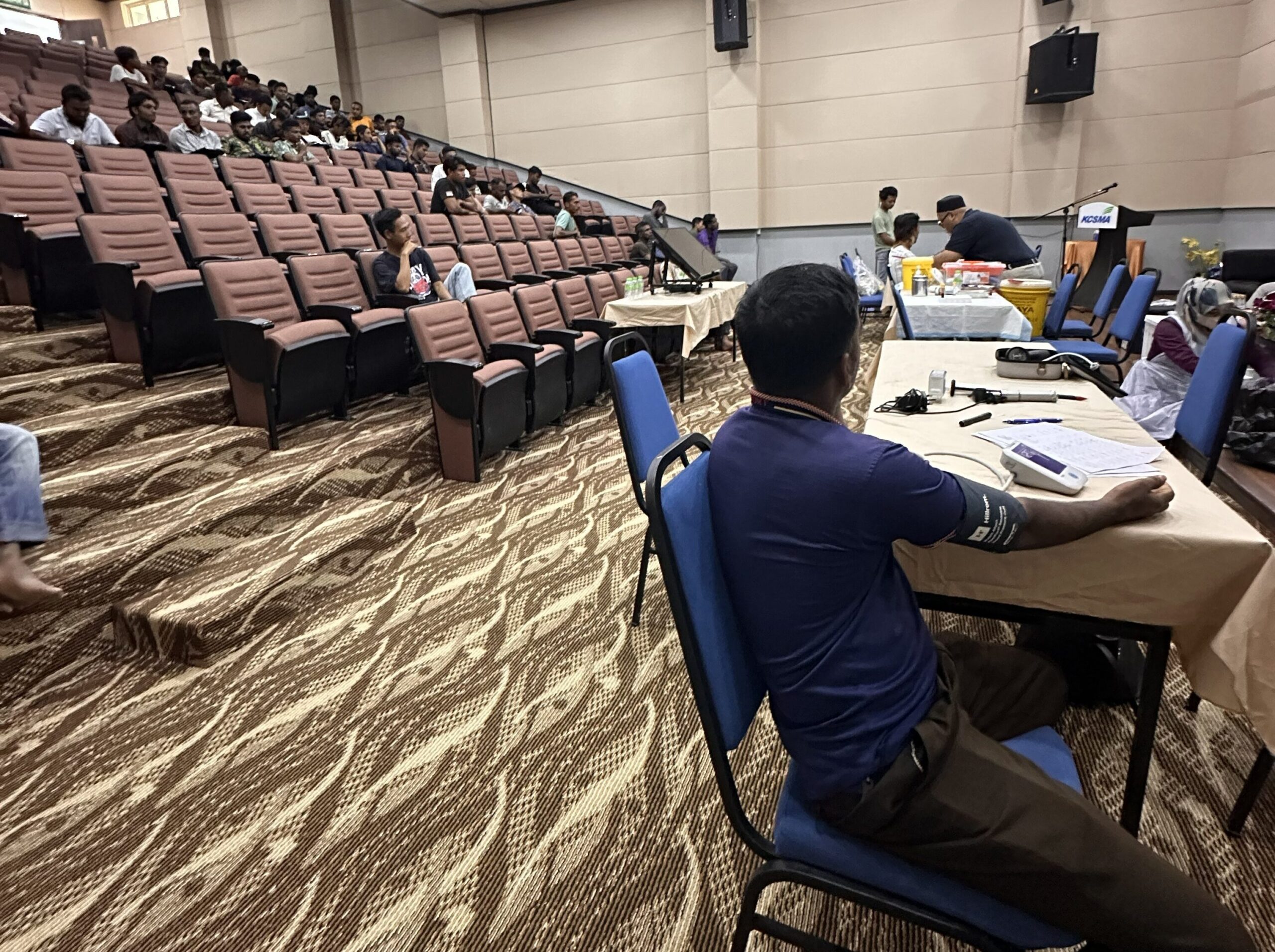 Pemeriksaan tekanan darah seorang pekerja semasa program kesihatan pekerjaan bersama KOSMA