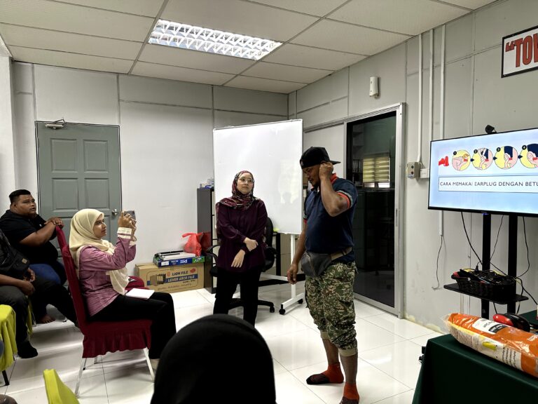 Seorang peserta menunjukkan cara memakai earplug dengan betul di hadapan peserta lain
