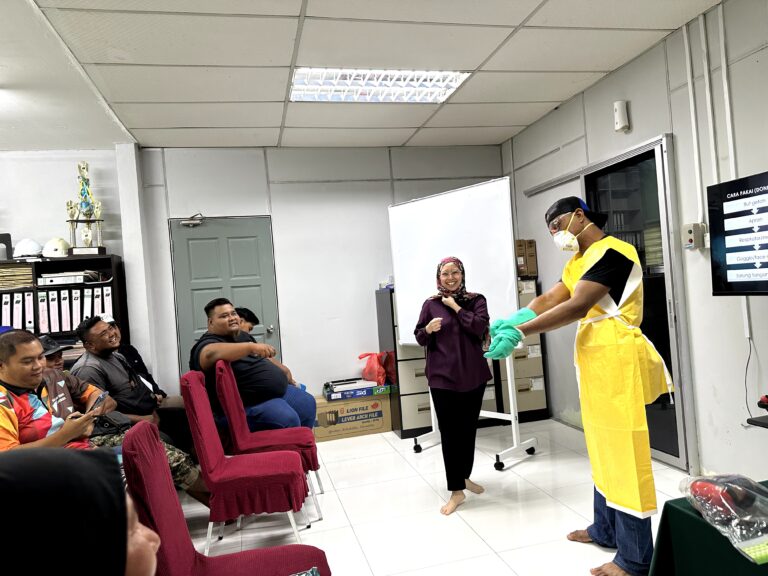 Demonstrasi pemakaian apron dan sarung tangan perlindungan semasa latihan pengendalian bahan kimia