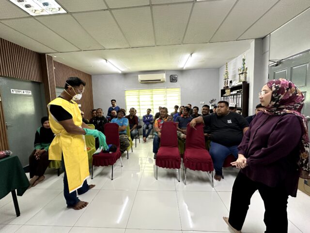Dr. Khairimi Mohamad memerhati demonstrasi pemakaian PPE di hadapan peserta latihan THP Kota Bahagia