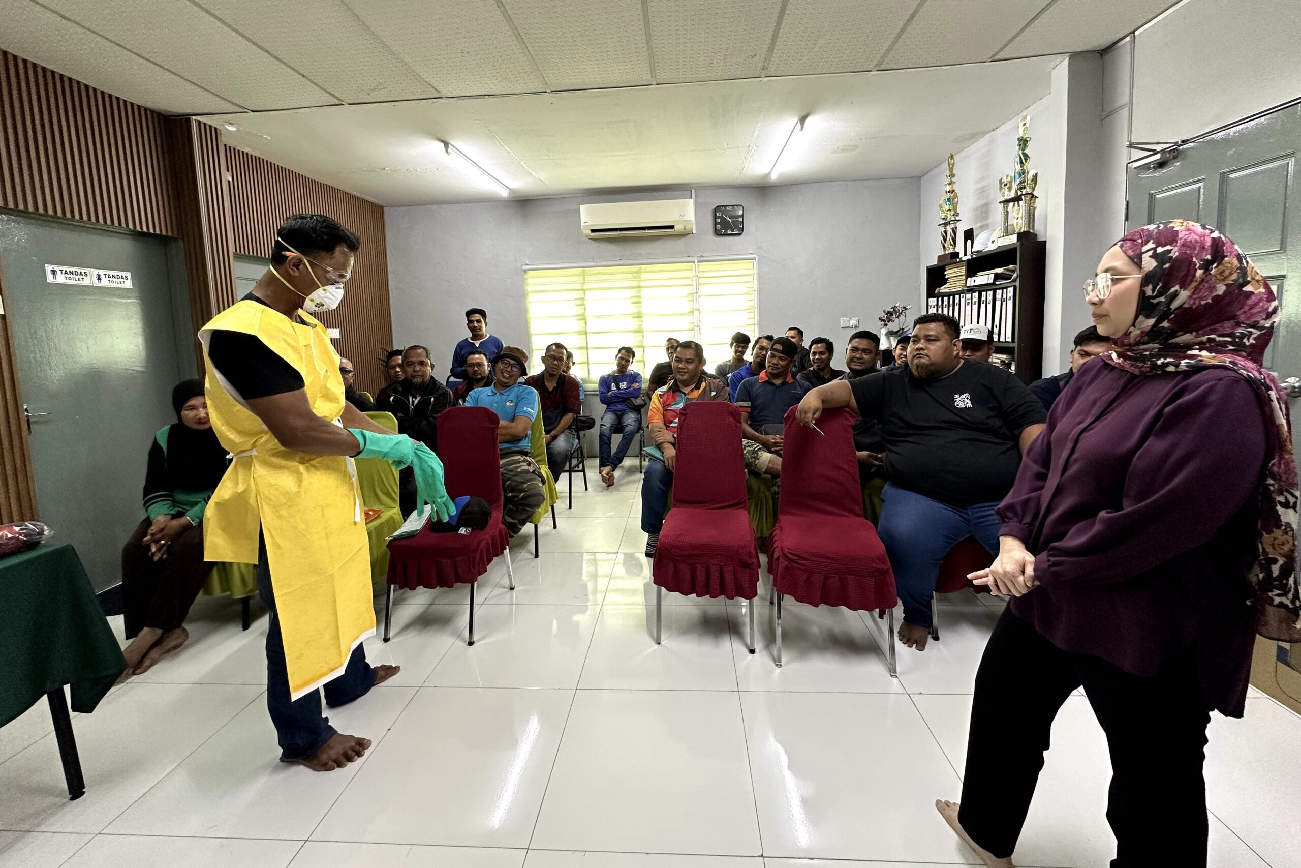 Dr. Khairimi Mohamad memerhati demonstrasi pemakaian PPE di hadapan peserta latihan THP Kota Bahagia